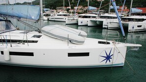 A white yacht docked at a marina with other boats, a star symbol on the side, and a blue tarp on the mast. - Dubrovnik Delight: A Sun-Kissed Sailing Experience (Komolac)