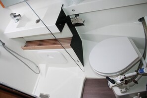 Et badeværelse med hvid vask, toilet og bruseniche.