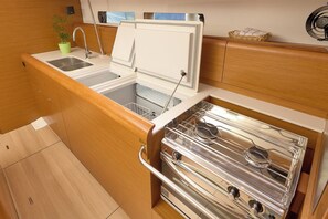 A compact kitchen with a sink, stove, and storage cabinets. - Sun-kissed Sailing Adventure in Split-Dalmatia, Croatia (Trogir)