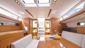 A yacht interior with a dining area, a galley, and a seating area with a view through the windows. - Sun-kissed Sailing Adventure in Split-Dalmatia, Croatia (Trogir)