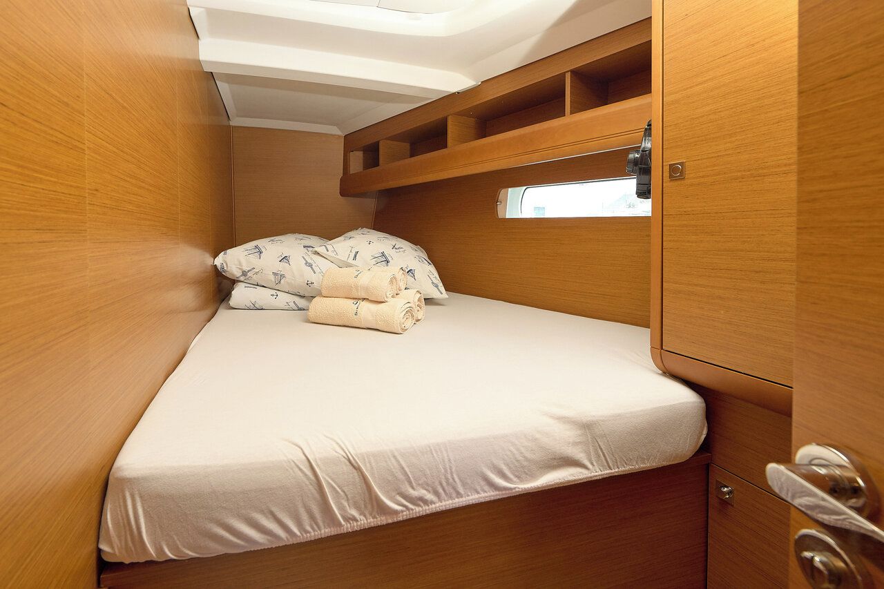 A compact cabin with a bed, storage compartments, and a small window.