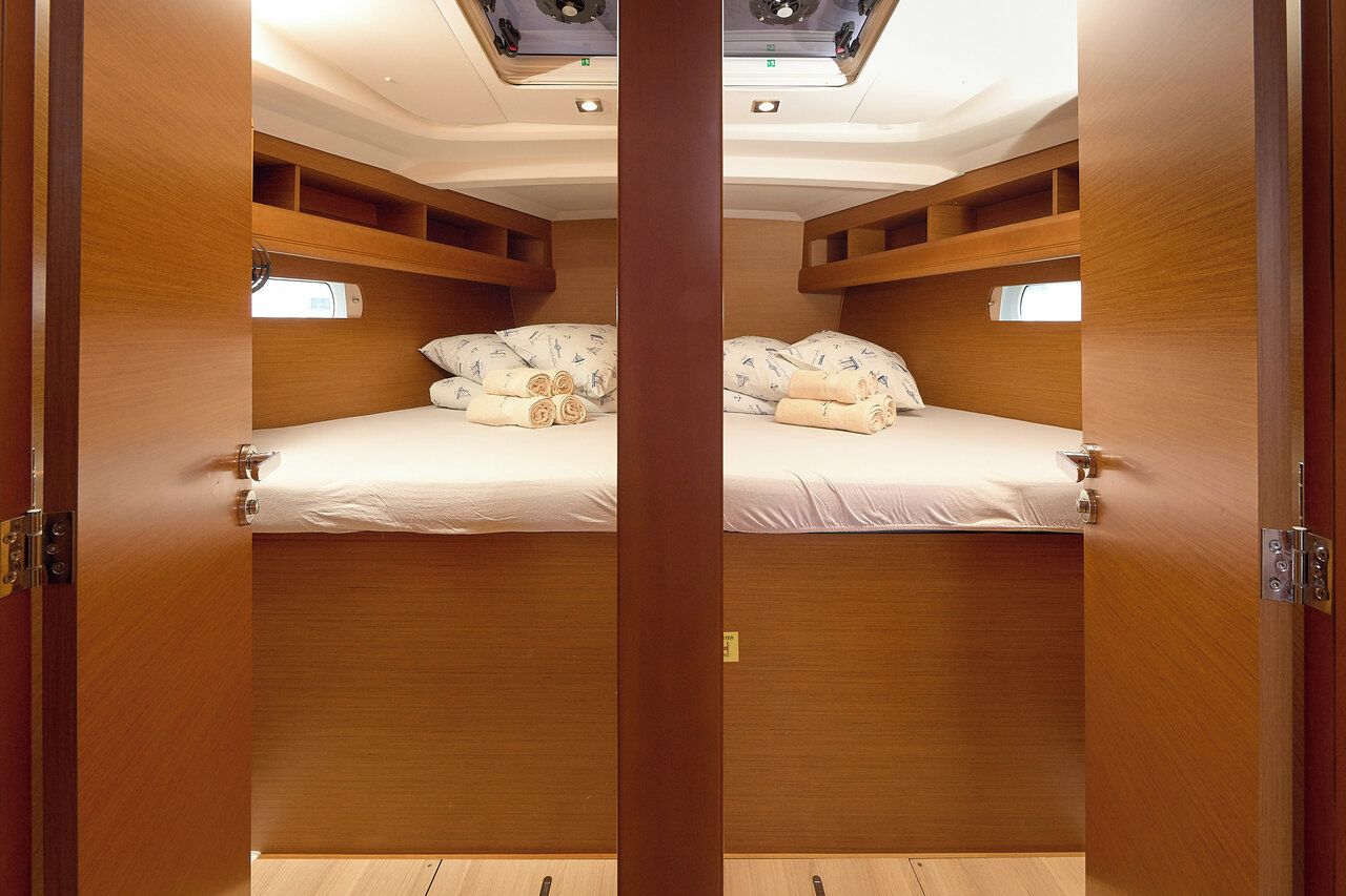 A cabin with two beds, wooden paneling, and a skylight.