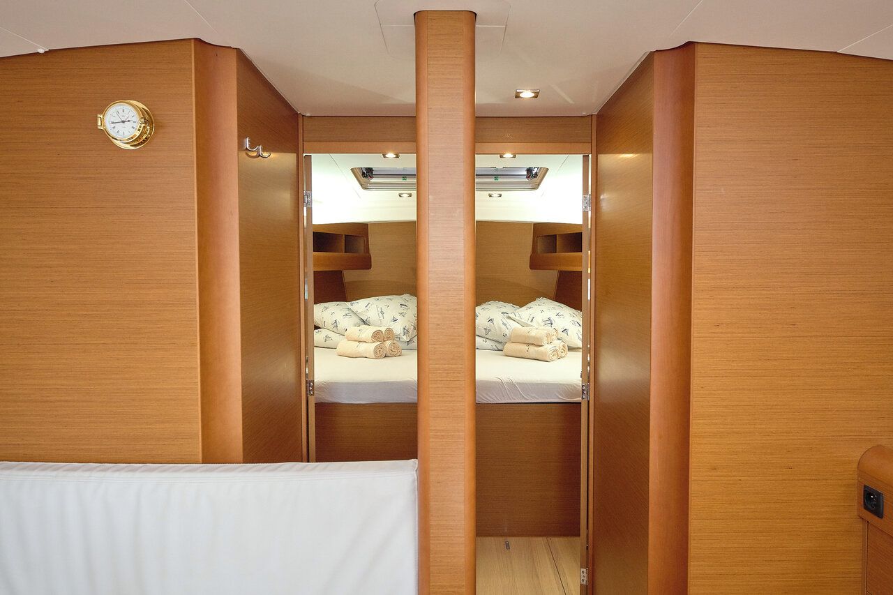 A cabin with wooden walls, a bunk bed, a clock, and a small shelf.
