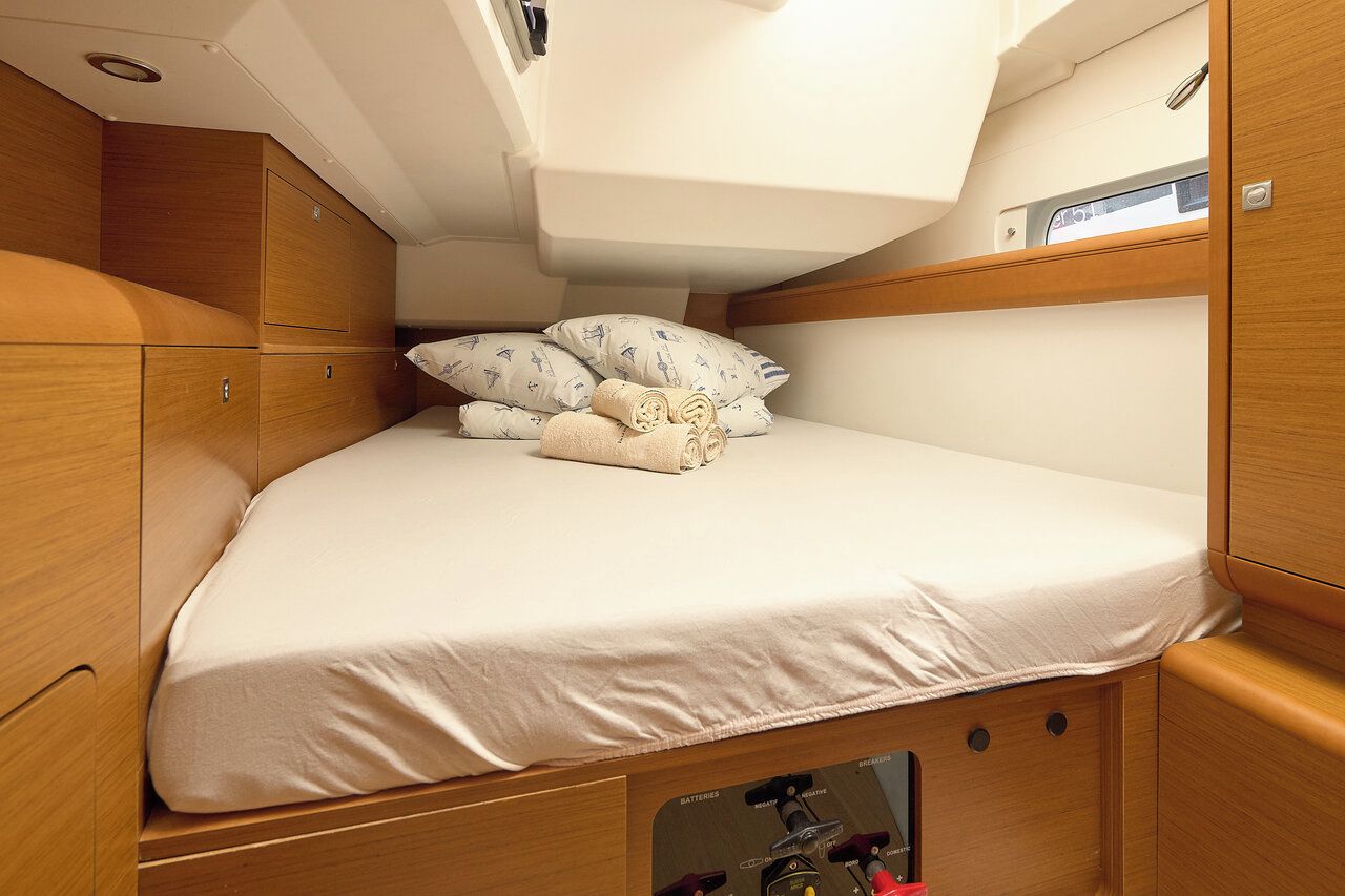 A compact cabin with a bunk bed, wooden cabinetry, and a small storage compartment.