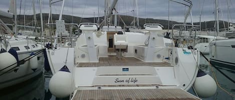 A marina with boats docked, a wooden deck, and a cabin with 'Sun of life' on the side.
