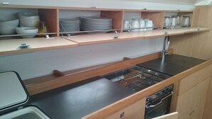 Een kleine keuken met een fornuis, spoelbak en planken voor servies en glazen.