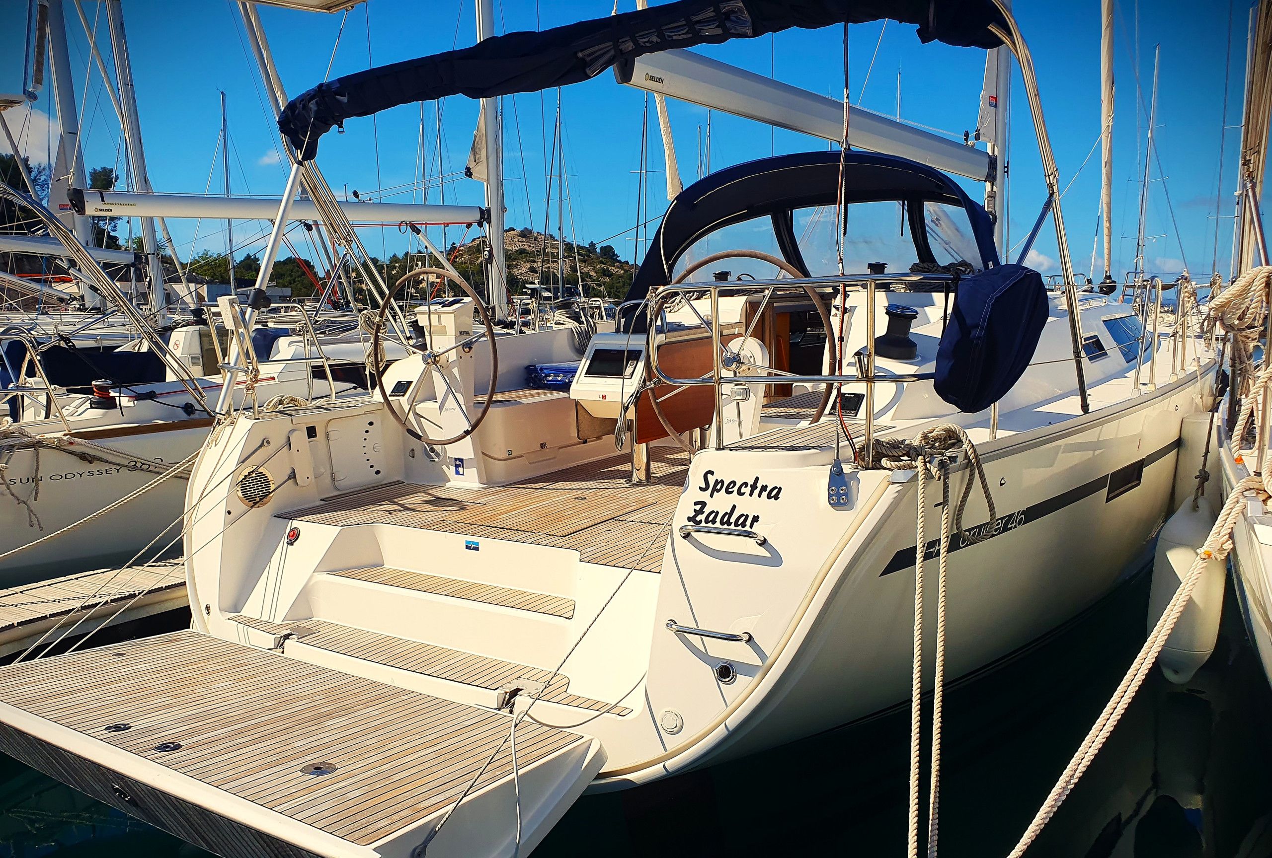 A sailboat named 'Spectra Zadar' docked at a marina with other boats.