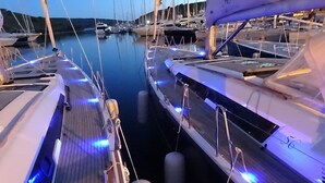 Un puerto deportivo con barcos amarrados, muelle de madera e iluminación azul.