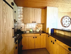 A kitchen with wooden cabinets, a stove, and a sink.