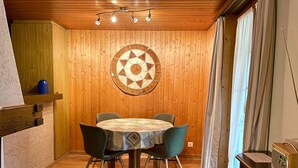 Comedor con una mesa redonda, cuatro sillas y una pared de madera con un tapete circular.