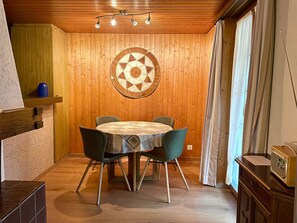 Ein Essbereich mit einem runden Tisch, vier Stühlen und einer Holzwand, belegt mit einem runden Teppich.