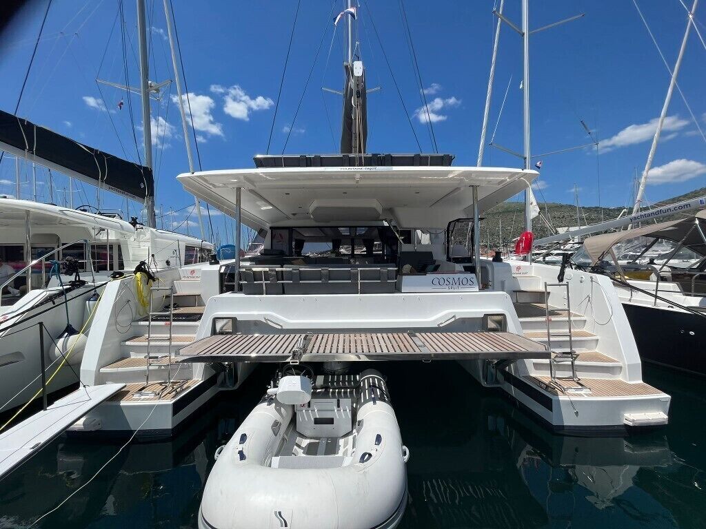 A yacht docked at a marina with a covered deck area, a seating arrangement, and a small inflatable boat.