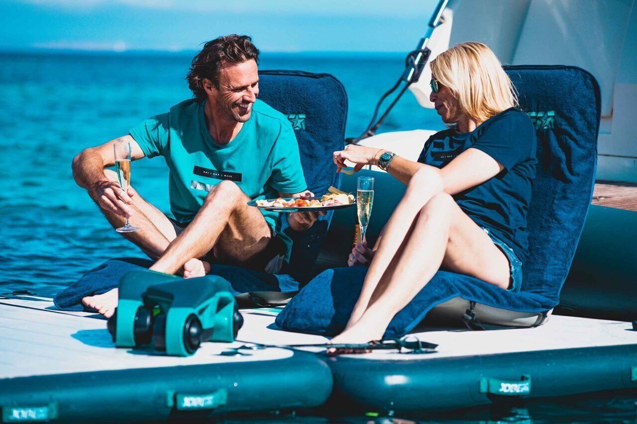 Twee personen in een boot, compleet met een eettafel, een waterfles en een reddingsvest.