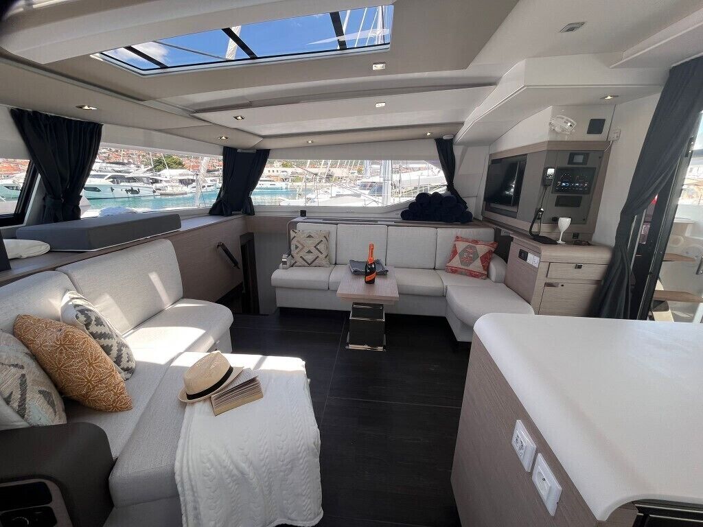 Schickes Yacht-Interieur mit einer Sitzecke, einem kleinen Tisch, einem Fernseher und Blick auf den Hafen.