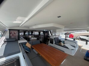 Bootinterieur met een eetgedeelte, zitplaatsen en uitzicht op de jachthaven.