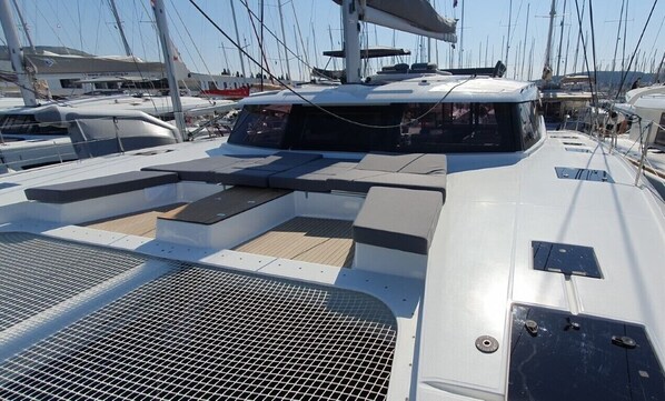 Een dek van een boot met zitgedeeltes, een lier en een mast.