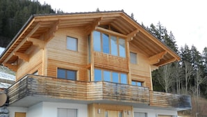 Ein zweistöckiges Holzhaus mit Balkon, großen Fenstern und einer Garage.