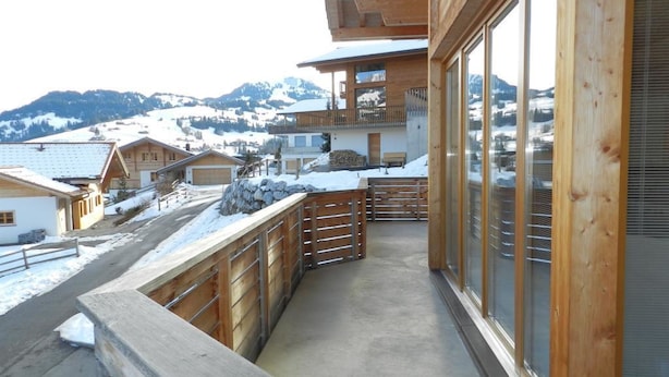 Ein Holzbalkon mit Blick auf schneebedeckte Häuser und Berge.