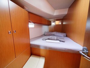 Une petite cabine comprenant un lit, des placards de rangement et un petit banc.