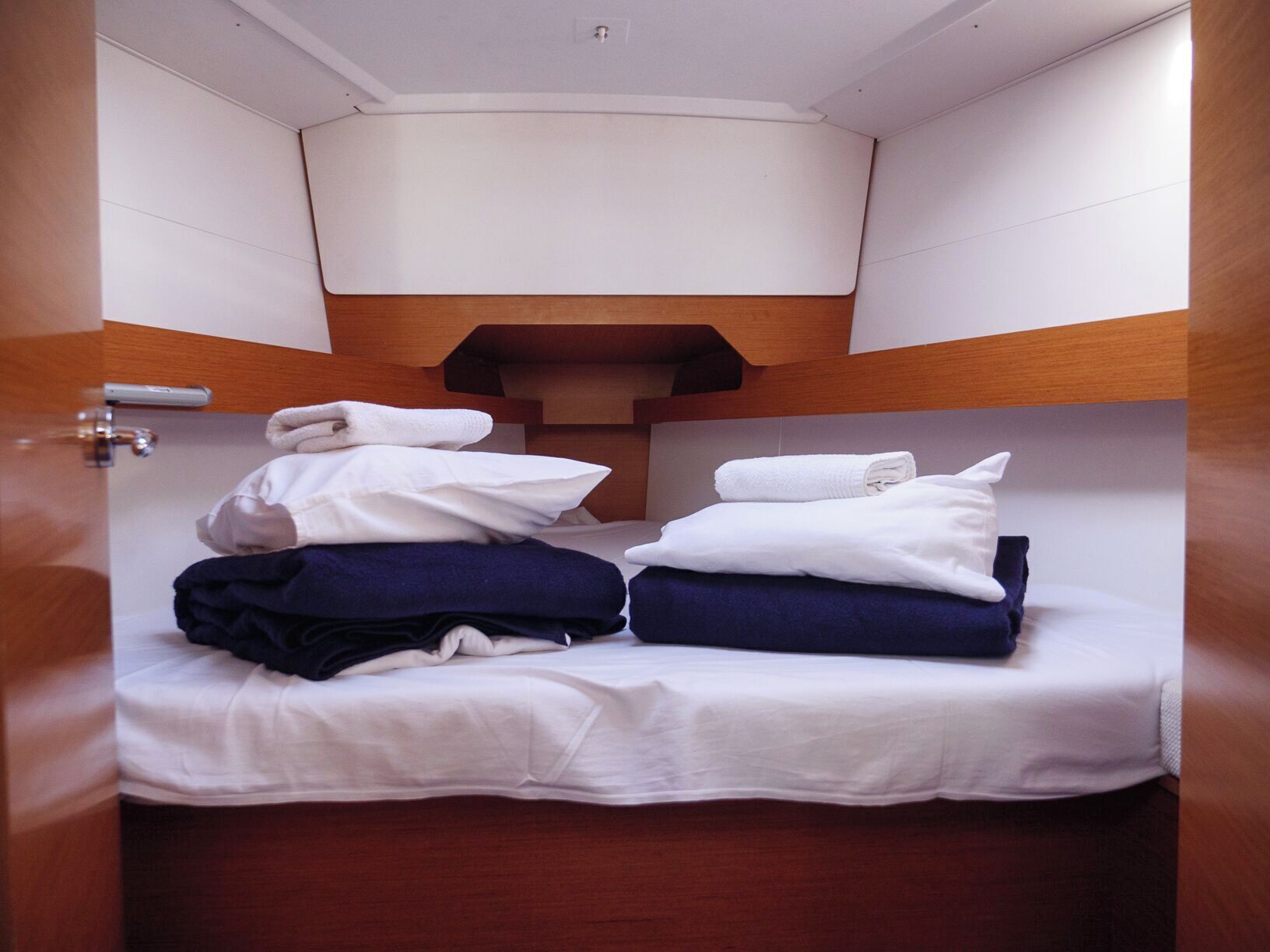 Une petite pièce, de taille modeste, avec un lit superposé, une tête de lit en bois et un plafond blanc.