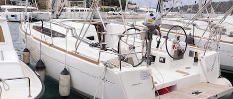 A white yacht docked at a marina with a cabin, a small deck, and a lifebuoy.