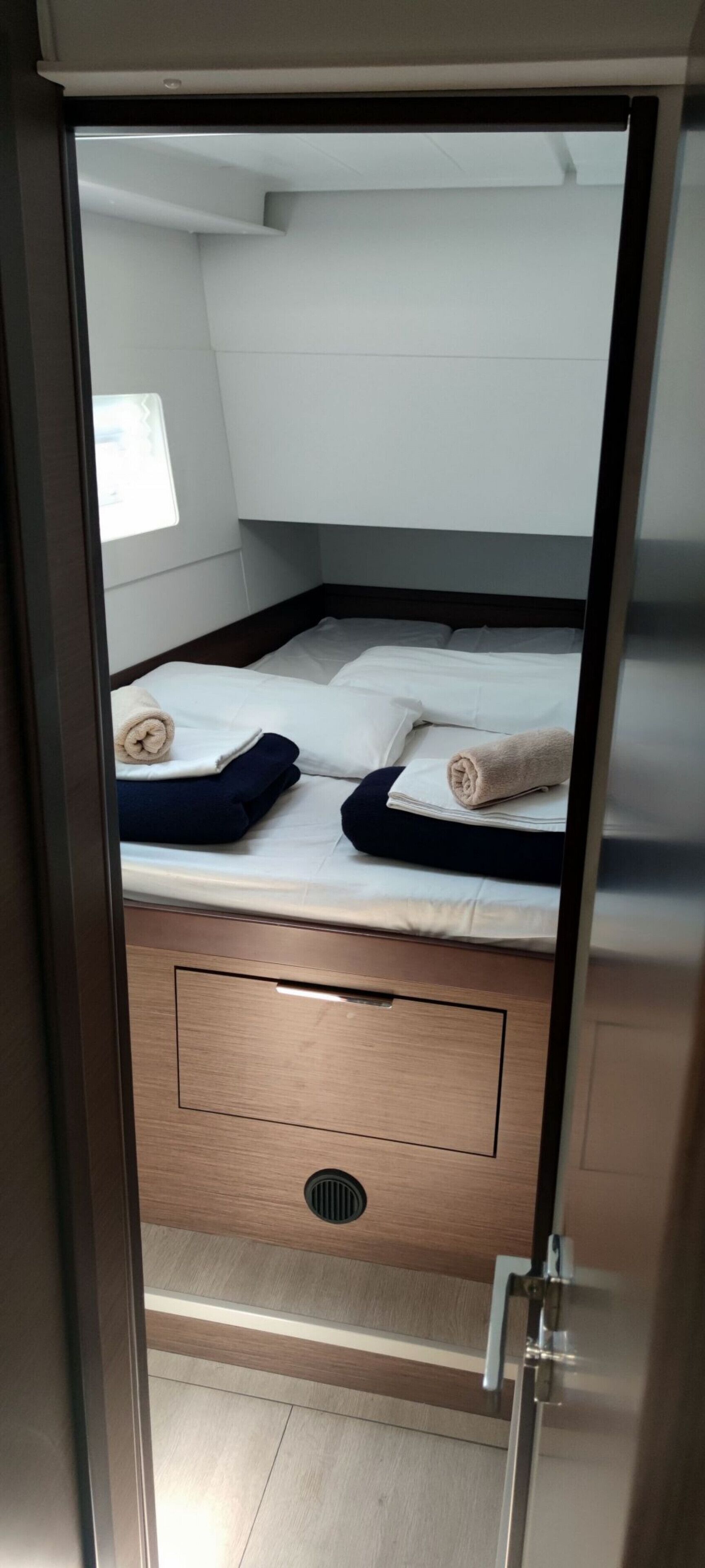 A room with a bed, a wooden drawer unit below, and a window.