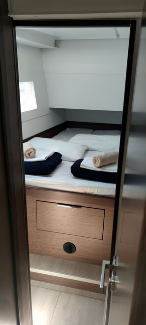 A compact room with a bed, a small drawer, and a window. - Sun-Kissed Sailing Adventure in Split, Croatia (Rogac)