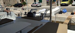 A boat deck with seating, a mast, and a lifebuoy. - Sun-Kissed Sailing Adventure in Split, Croatia (Rogac)