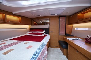 Un interior compacto y bien iluminado con una cama, un escritorio y una pequeña zona de estar.