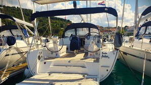 Ein Yachthafen mit vertäuten Booten, darunter ein Boot namens 'Nabu Zadar' mit Holzdeck und Steuerrad.