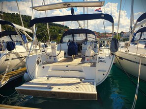 Ein Yachthafen mit vertäuten Booten, darunter ein Boot namens 'Nabu Zadar' mit Holzdeck und Steuerrad.