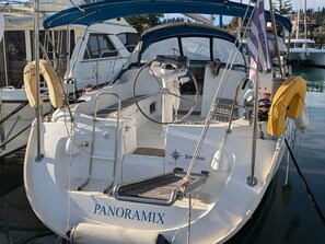 A boat named 'PANORAMIX' docked at a marina with a white hull, blue canopy, and visible deck equipment. - Sun-Kissed Sailing Adventure in the Ionian Islands (Kontokali)