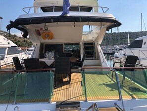 Ein Bootsdeck mit Tisch, Stühlen, einem Rettungsring und einer Flagge.