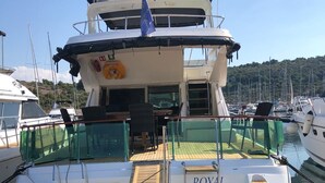 Een jacht genaamd 'ROYAL SPLIT' ligt aangemeerd in een jachthaven met een houten dek, een zitgedeelte en een reddingsboei.