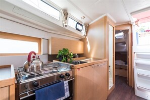 A compact RV kitchen with a stove, sink, and a small plant. - Sun-kissed Sailing Adventure in Istria, Croatia (Pomer)