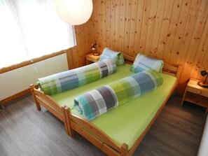A single-bed room with a wooden floor, a green mattress, and a wooden headboard. - Résidence Sonnegg (Vuilleumier) Appartement/Fewo, Dusche oder Bad, WC by Interhome (Zweisimmen)