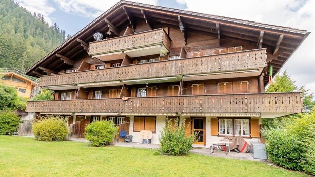 Un chalet de madera tradicional con varios balcones y un amplio porche delantero.