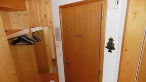 Un pasillo estrecho con paredes de madera, una puerta, un perchero y un pequeño adorno navideño.