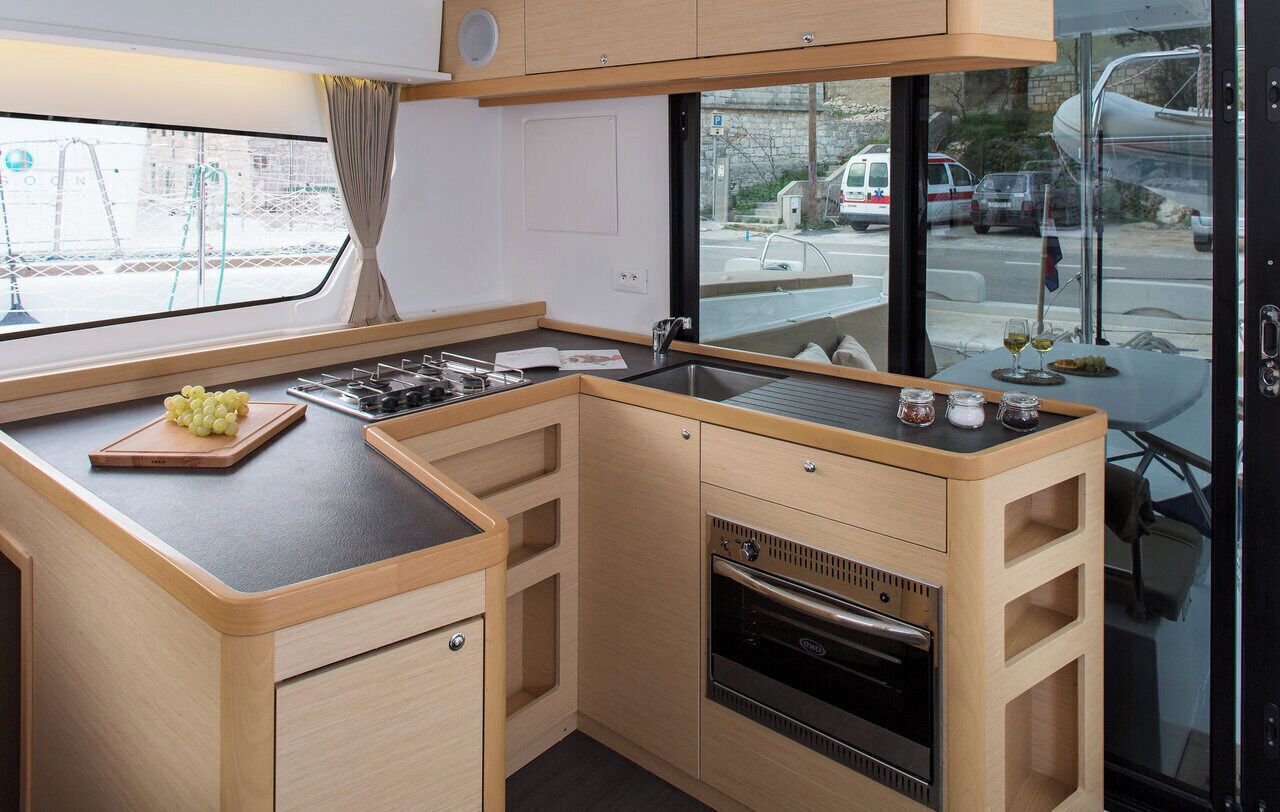 A compact kitchen with a built-in oven, a sink, and a window overlooking a street.