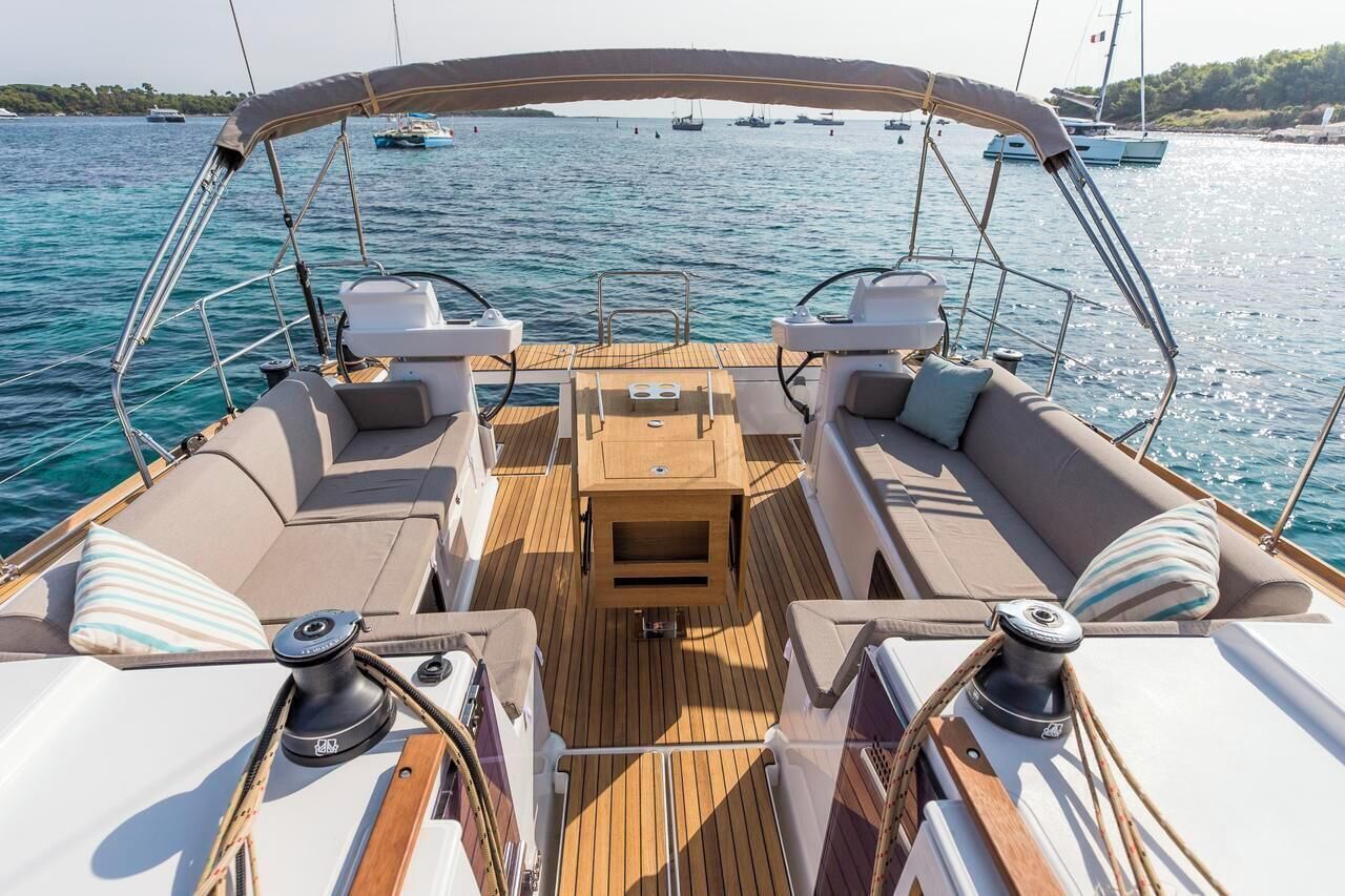 Un pont de bateau doté d’un espace salon couvert, d’une table centrale et d’une vue sur l’eau et les autres bateaux.