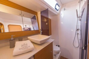 A modern bathroom with a large mirror, a white sink, a towel with 'DUFOUR YACHTS' logo, a shower, and a toilet. - Sun-Kissed Sailing Adventure in Sibenik, Croatia (Primošten)