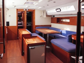A compact interior with a dining area, seating, and a small refrigerator. - Sun-Kissed Sailing Adventure in Split, Croatia (Rogac)
