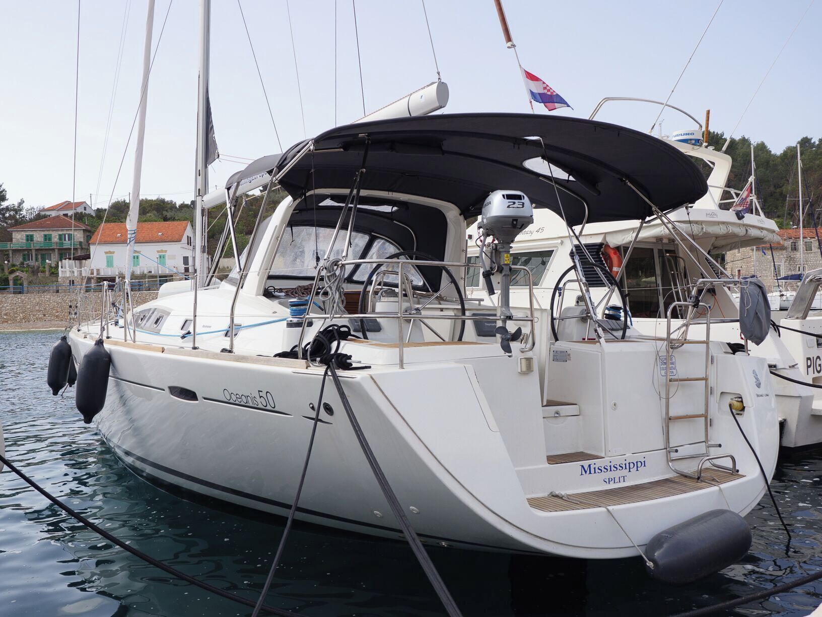 Eine weiße Yacht namens 'Mississippi' liegt in einer Marina mit überdectem Deck und mehreren Masten vor Anker.