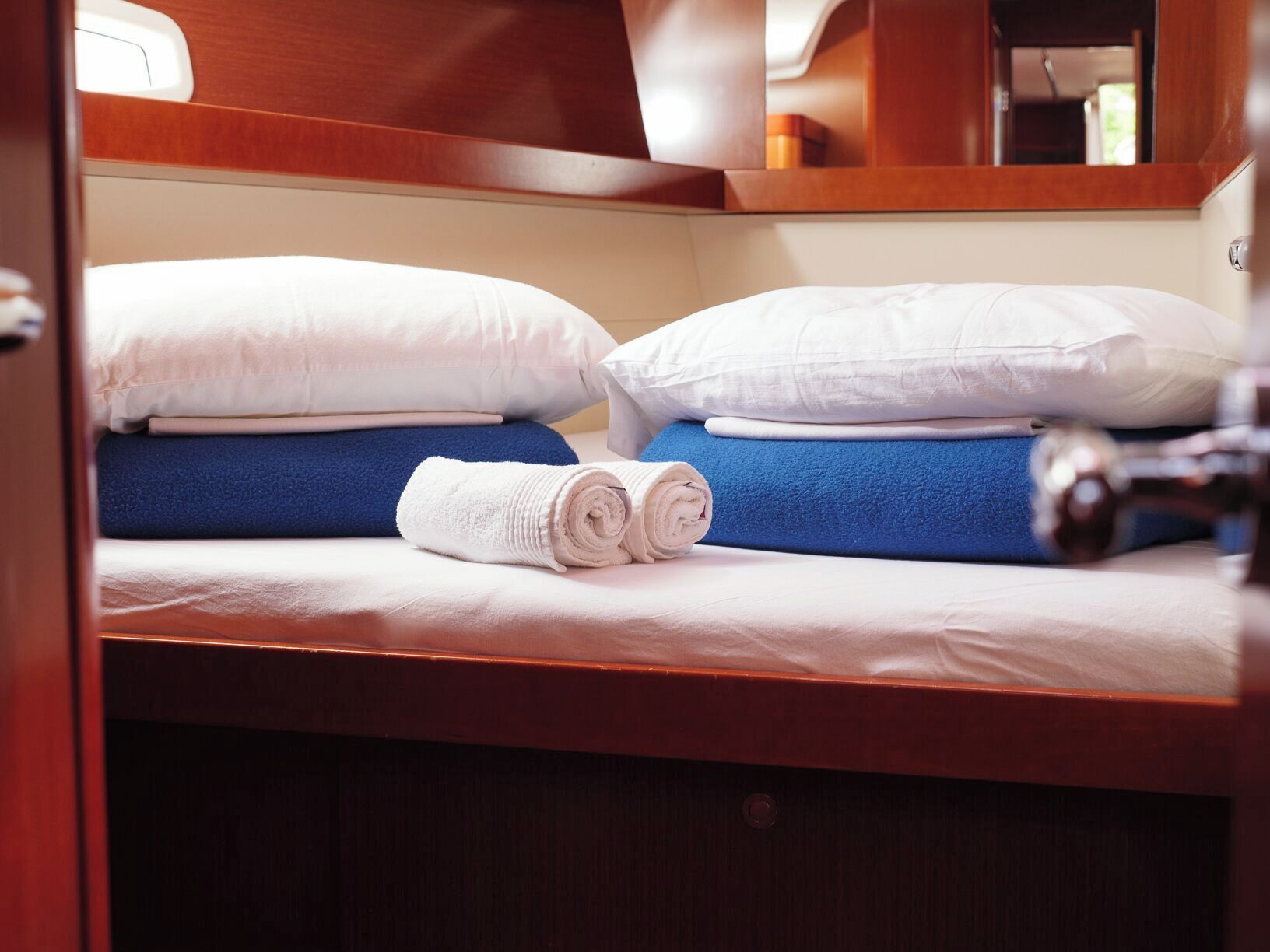 A cabin with a bunk bed, a rolled white towel, and a wooden headboard.