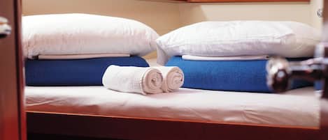 A cabin with a bunk bed, a rolled white towel, and a wooden headboard.