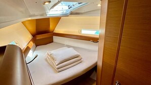 Una cabina compatta e ben illuminata, con un letto, un tavolino e un armadio.