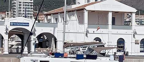 Un yate blanco llamado 'WHISKY' atracado cerca de un edificio blanco con puertas arqueadas y un letrero que dice 'Porto de Mouro'.