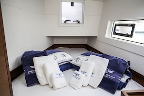 Ein ordentlich bezogenes Bett mit Handtüchern und Kopfkissen, ein Fenster mit Blick und ein kleines Fenster über dem Bett.