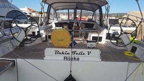 En båt som heter ”Bahia Feliz V Rijeka”, utrustad med ett ratt, ett gult skydd och en svart boj.