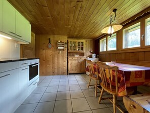 Un interior de madera con cocina, comedor y ventana con vistas.